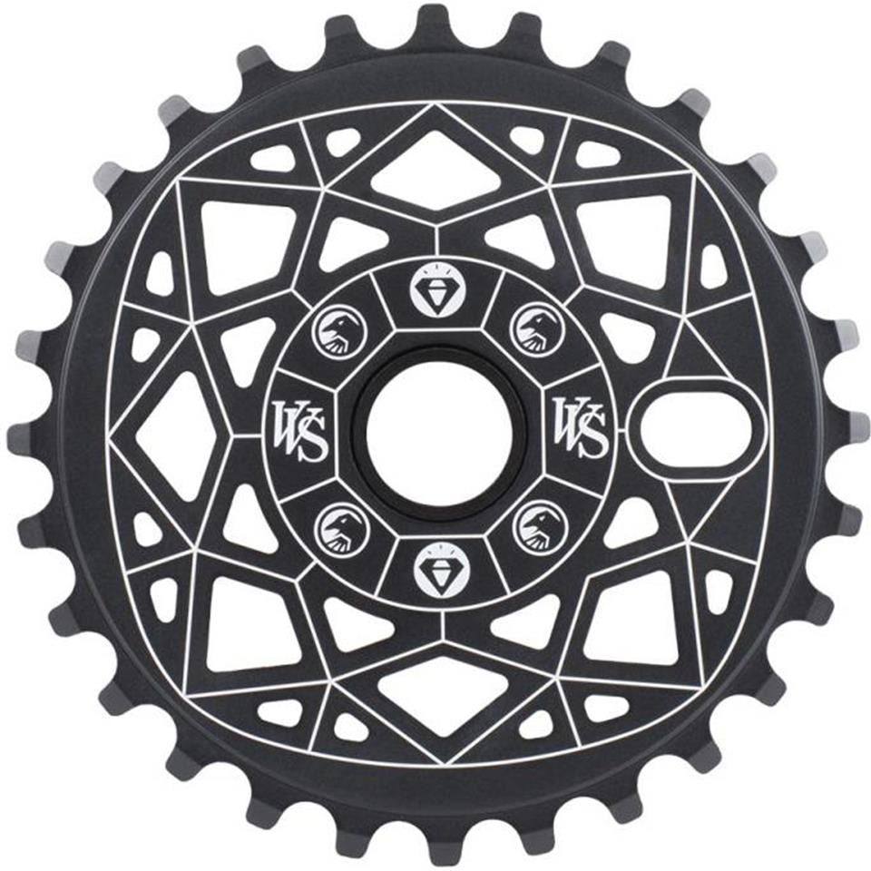 The Shadow VVS Sprocket is a black chainring made from 7075 alloy, adorned with white geometric patterns and symbols.