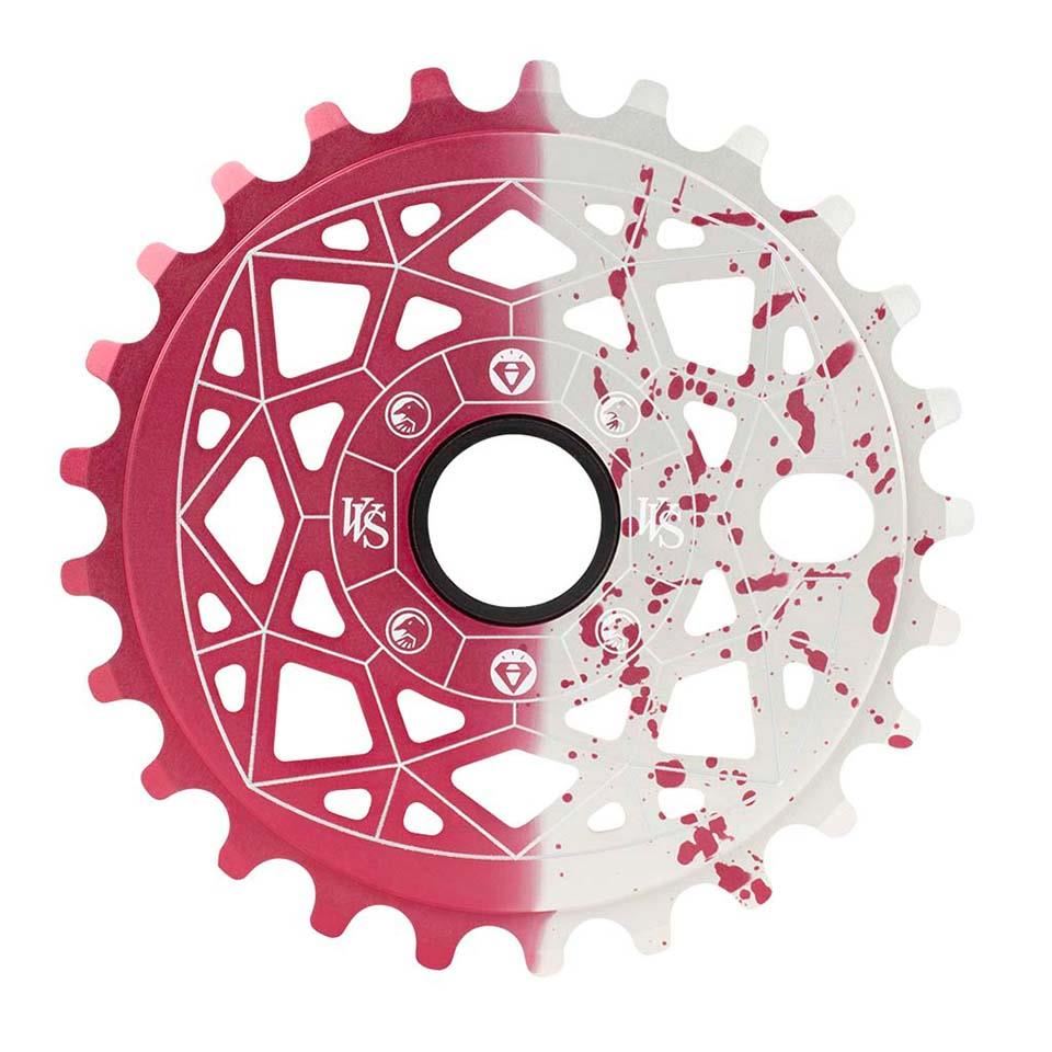 Introducing the Shadow VVS Sprocket, a dual-tone chainring made from 7075 alloy, featuring geometric cutouts and a red and white paint splatter design with a central circular opening for optimal performance.