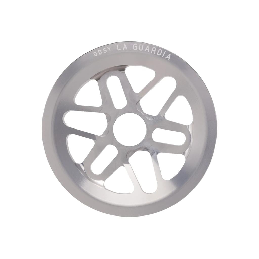 The Odyssey La Guardia Bolt Drive Sprocket is a silver BMX sprocket with eight cutout spokes and "ODSY LA GUARDIA" engraved on the top edge, featuring full guard protection.