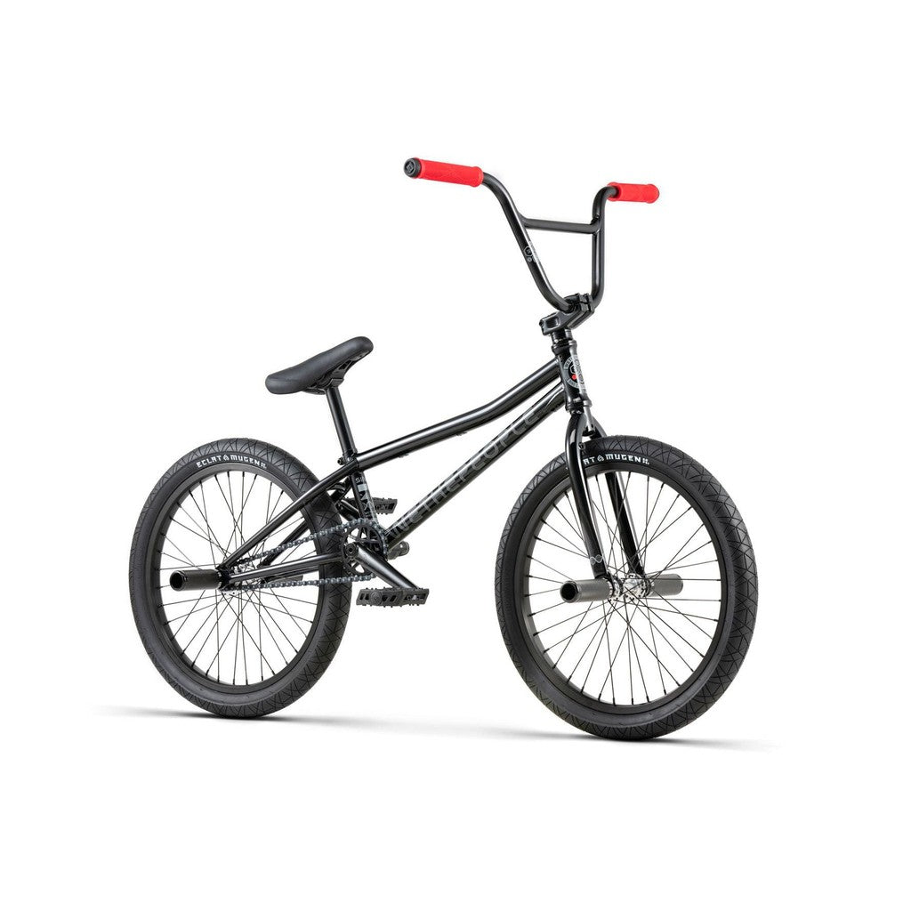A Wethepeople Sinus Flatland 20 Inch Bike, featuring a black diamond-shaped frame, red handle grips, flatland-specific Mugen tires, and a padded seat.
