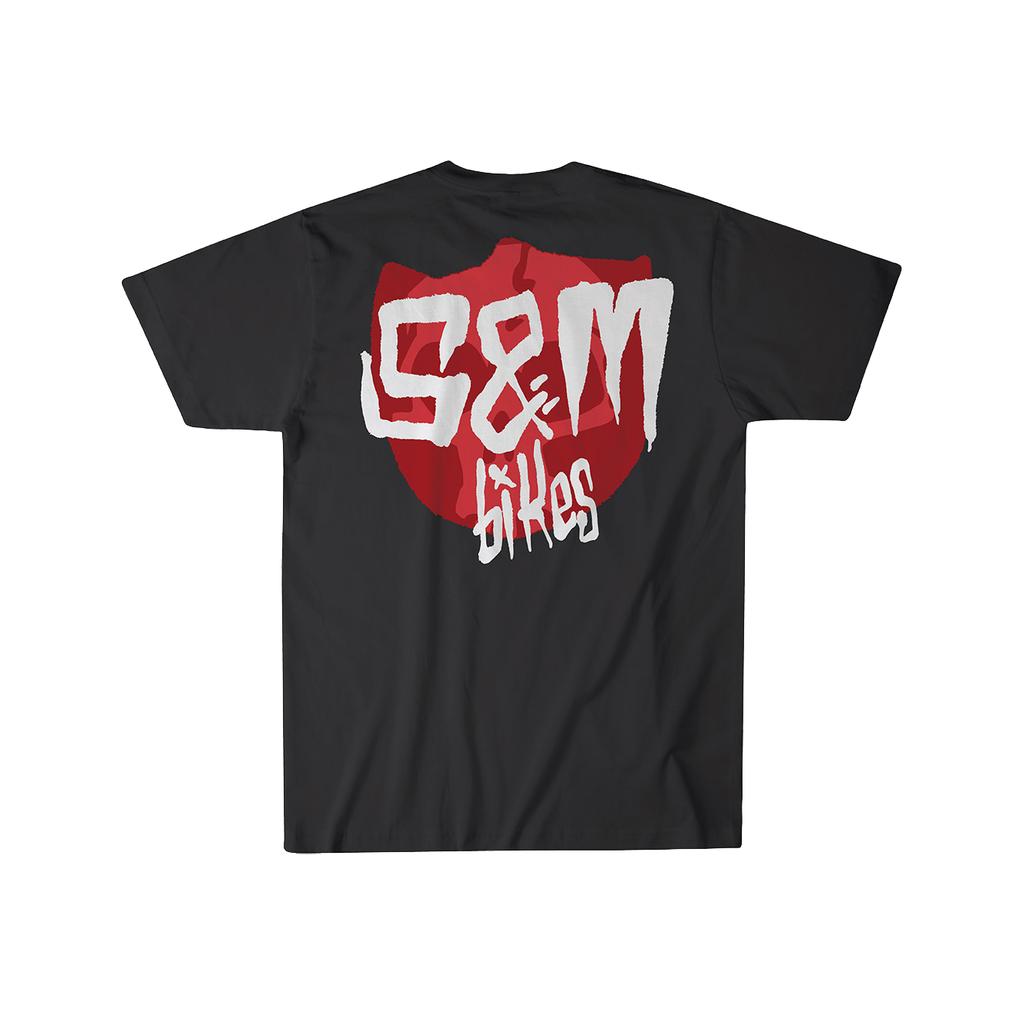 Check out the S&M Skull Shield T-Shirt! This sick black tee showcases a red shield with "S&M Bikes" in bold, white graffiti-style text on the back. Made from 100% combed cotton and printed in the USA, it offers both style and comfort.