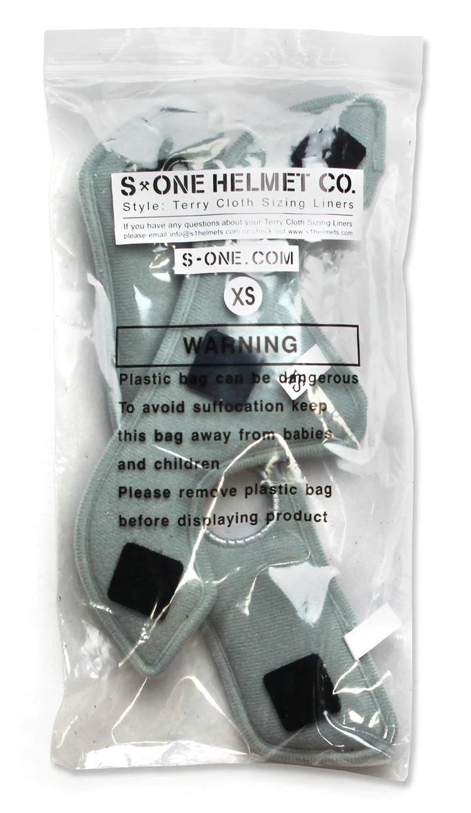 A clear plastic bag containing XS-sized S-One Helmet Wide Terry Cloth Liners, designed as washable sweat-absorbing replacements for helmet sizing. The bag has warning labels to keep out of reach of babies and children due to potential suffocation hazards.