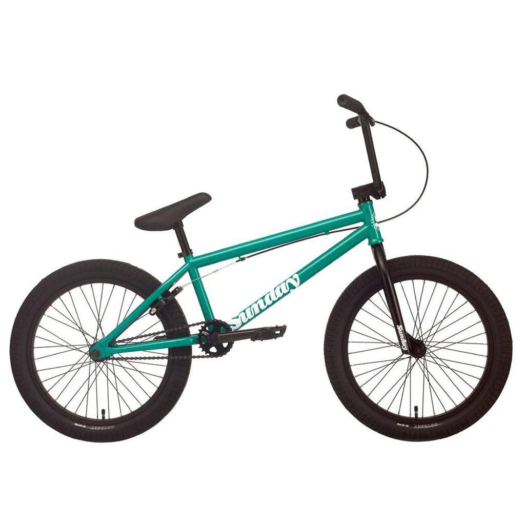 The Sunday Primer 20 Inch Bike features a teal frame with black handlebars, seat, and wheels. The brand name "Sunday Primer" is printed in white on the frame, offering pro-level geometry that makes it an ideal starter bike.