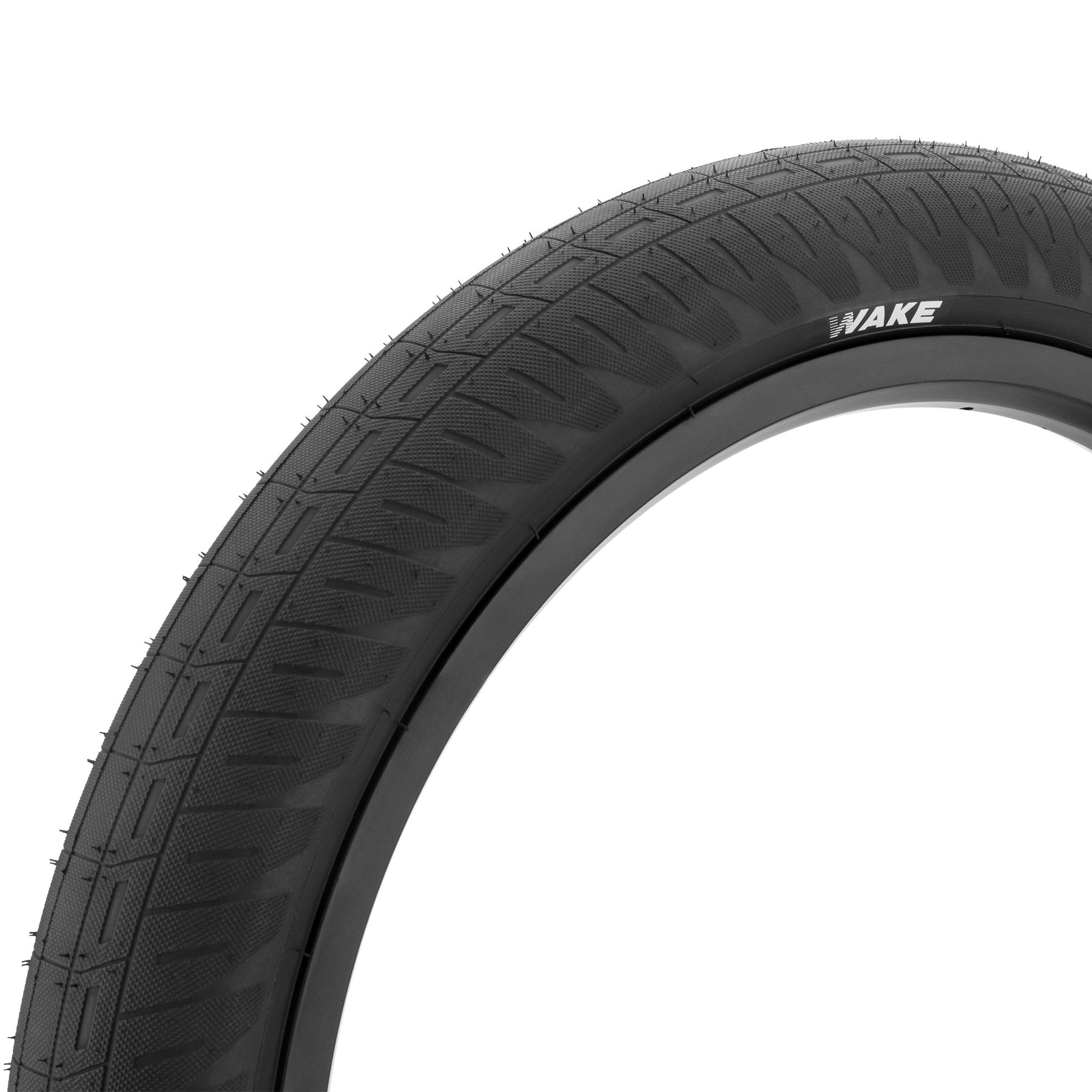 Close-up of the Kink Wake 20 Inch Tyre, a black BMX tire featuring a wide, grippy tread pattern with "WAKE" branding on the sidewall.