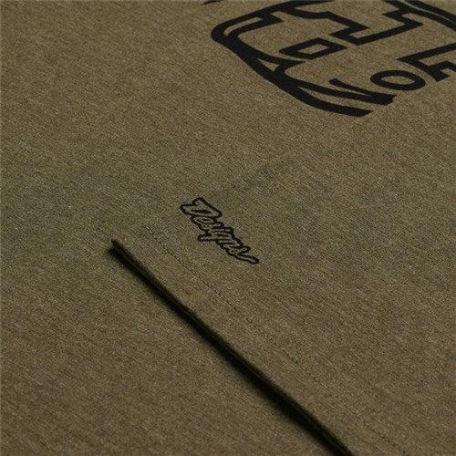 A close-up of the TLD 25.1 Badge SS T-Shirt in olive green features subtle black "Design" lettering, echoing the Troy Lee collection style.