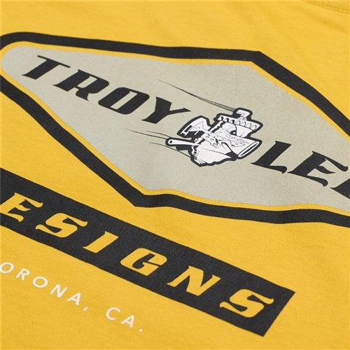 The TLD 25.1 Carb SS T-Shirt is yellow with a "Troy Lee Designs" logo showing an artist's palette and brushes, along with "Corona, CA." Wear it to proudly represent TLD anywhere.