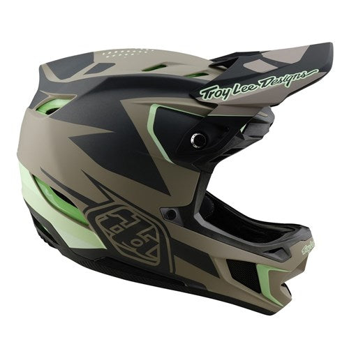 The TLD 25.1 D4 Composite Helmet (MIPS) / Optic Timber features a geometric green and black design, a peak visor, Troy Lee Designs branding, and enhanced MIPS protection for optimal downhill safety.