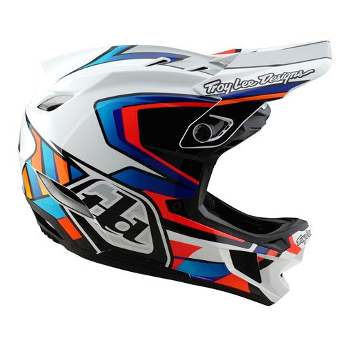The TLD 25.1 D4 Composite Helmet (MIPS) in White/Silver features geometric patterns and the Troy Lee Designs logo on the top and sides, offering colorful full-face coverage with MIPS Protection for enhanced safety during downhill adventures.