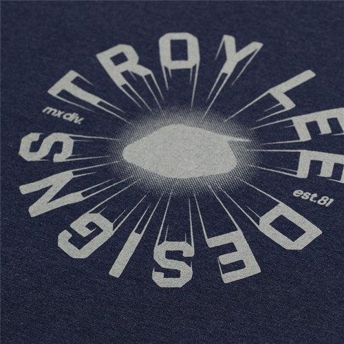 The TLD 25.1 Rotation SS T-Shirt features a close-up of dark fabric with a light-colored graphic design. "Designs Trx Lee" is central, with "mx div" and "est. 81" in corners—ideal for daily wear and embracing the good life.