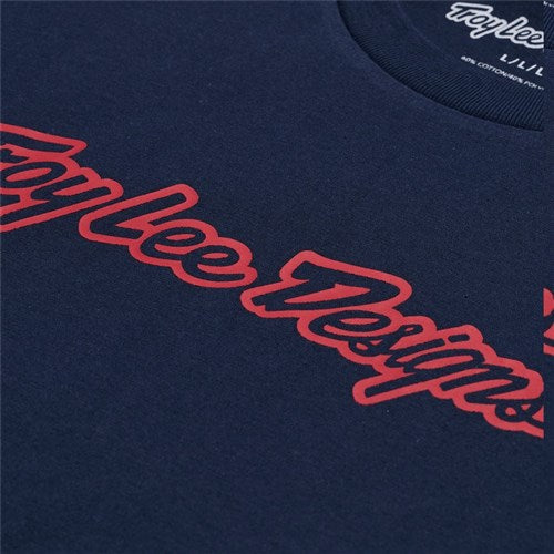 Close-up of a stylish navy blue TLD 25.1 Signature SS T-Shirt with "Troy Lee Designs" in red cursive across the chest, showcasing the brand's signature style.