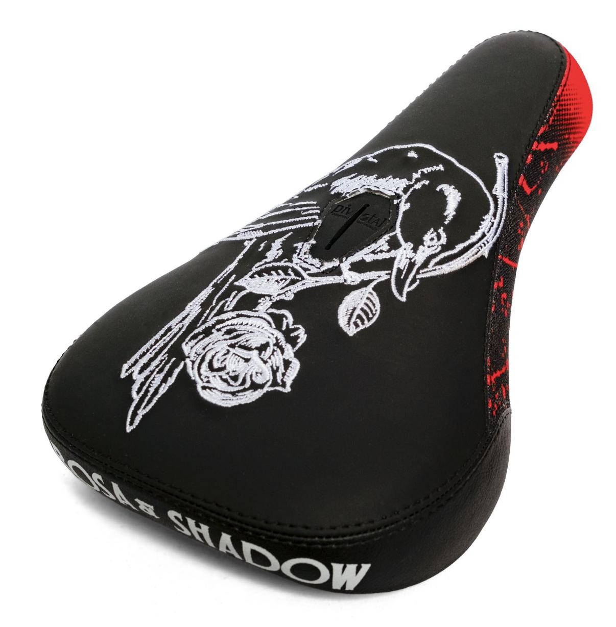 The Subrosa x Shadow Rose Crow Pivotal Seat is a black bicycle seat with white bird and rose embroidery, red rear accents, "SHADOW" side branding, and is a collaboration between Shadow and Subrosa.