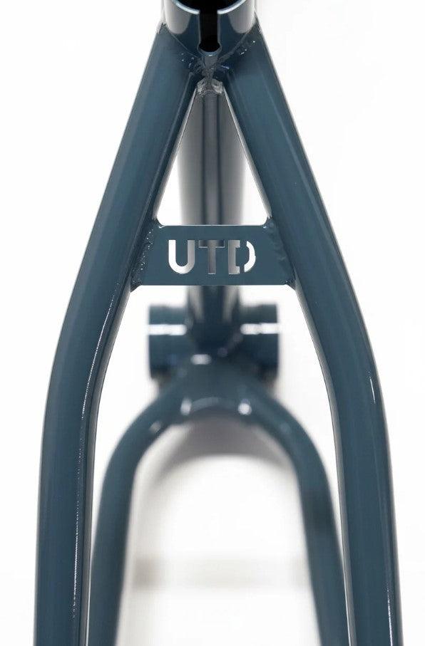 Close-up of the United Pro Model Frame (Marius Dietsche Signature) in blue, constructed from 4130 Sanko Japanese tubing, featuring a small plate connecting two diagonal bars with the letters “UTD” cut out.