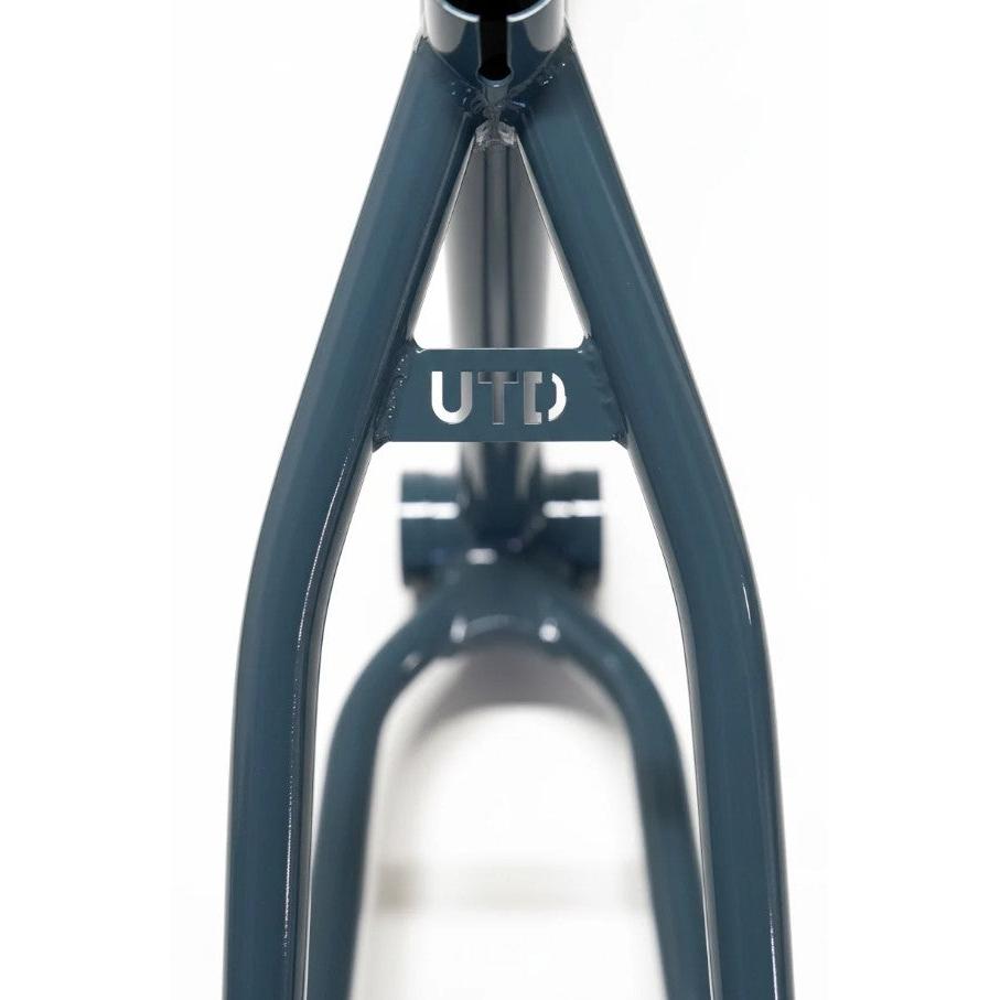 Close-up of the United Pro Model Frame (Marius Dietsche Signature) in blue, constructed from 4130 Sanko Japanese tubing, featuring a small plate connecting two diagonal bars with the letters “UTD” cut out.