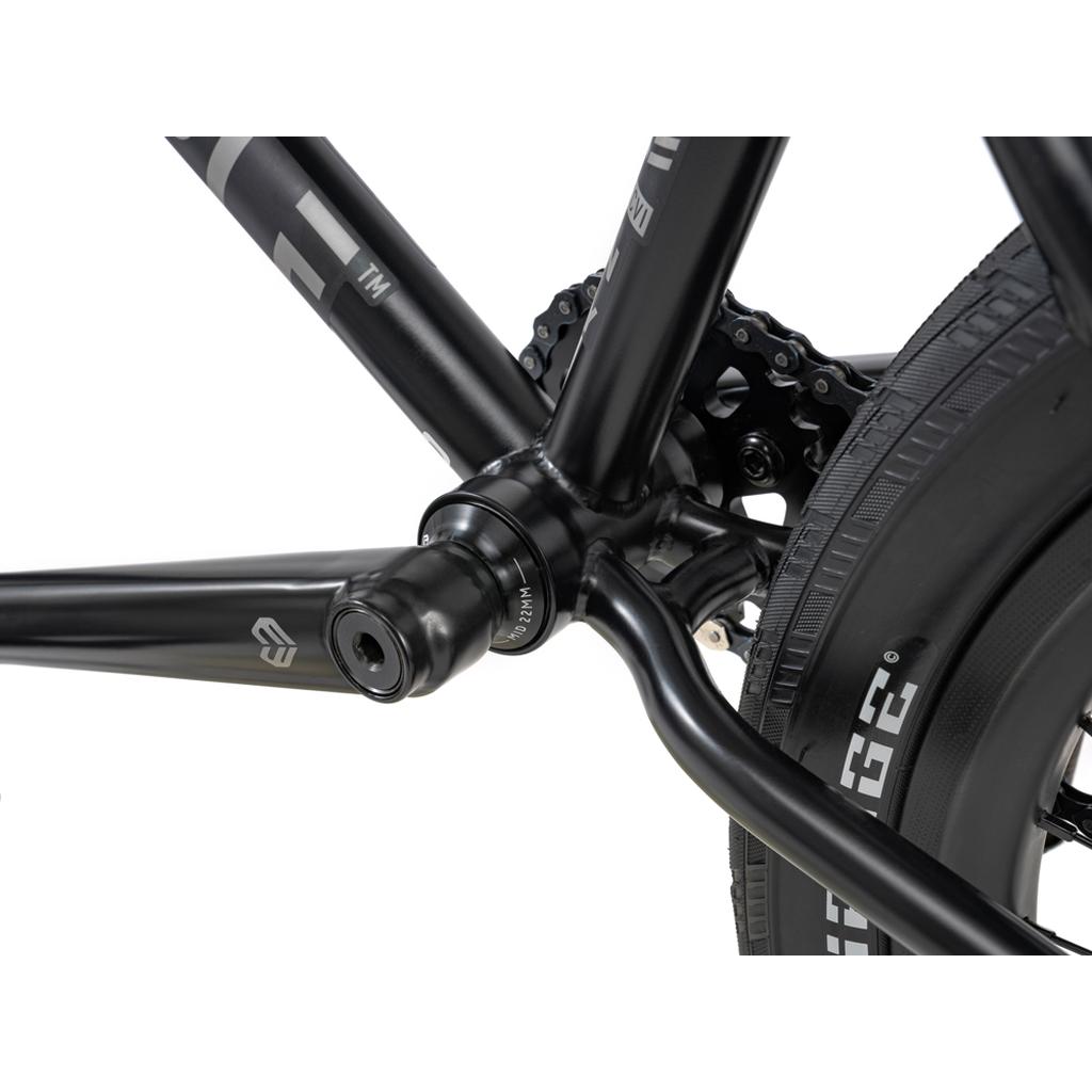 Close-up of the Wethepeople 20 inch Envy Carbonic LTD Bike’s crankset, bottom bracket, chainring, rear tire with carbon fibre rims, and detailed frame—showing part of the drivetrain.