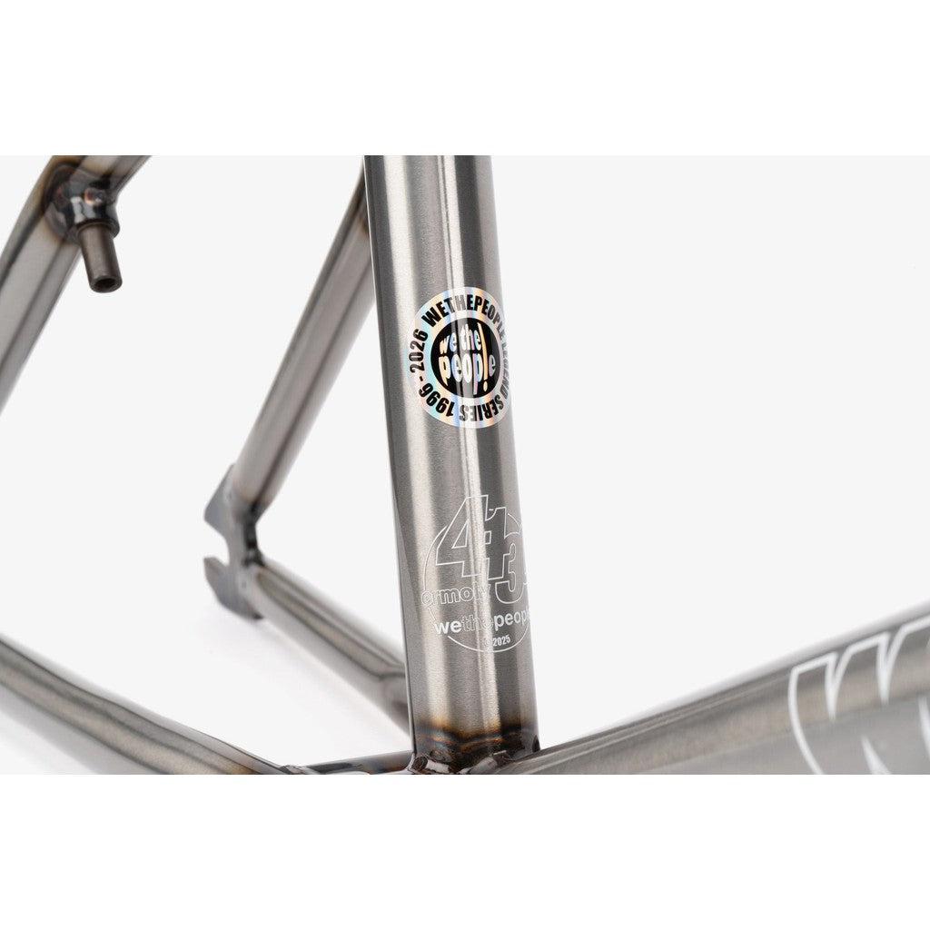 Close-up of a Wethepeople 4 Seasons BMX frame showing logos and text: "We The People" and "4130." This limited-edition reissue features a brushed metallic finish with expertly visible welds.
