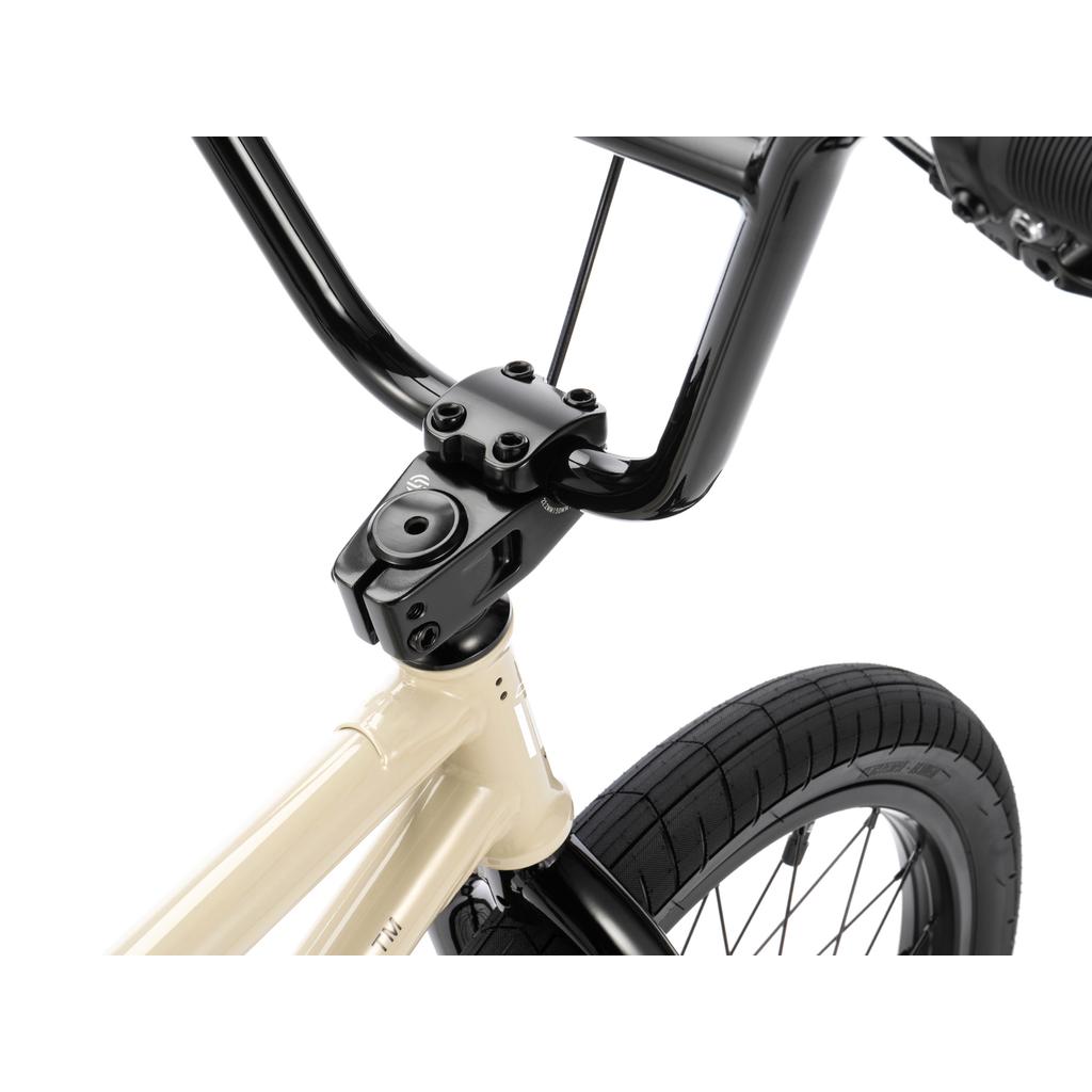 Close-up view of the Wethepeople Arcade 20 Inch Bike’s black front handlebars, Salt Comp stem, and part of the front wheel with a beige mid-tier frame.