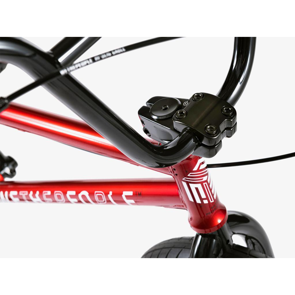Close-up of the Wethepeople Arcade 20 Inch Bike's handlebars, Salt Comp stem, and red frame, showing visible bolts and part of the front wheel against a white background.