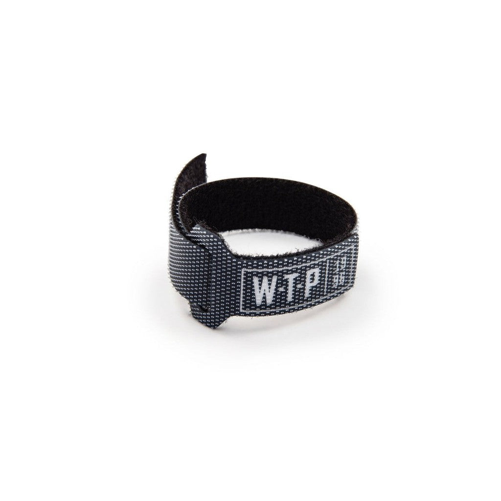The Wethepeople Brake Cable Velcro Holder is a black hook-and-loop tie featuring "WTF" and the WeThePeople logo in white, shown on a white background.