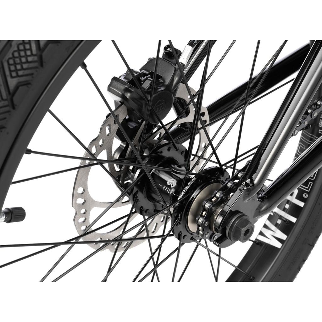 Close-up of the Wethepeople Havoc 20 Inch Bike's rear wheel, highlighting its hydraulic disc brake rotor, caliper, axle, spokes, and detailed tire tread.