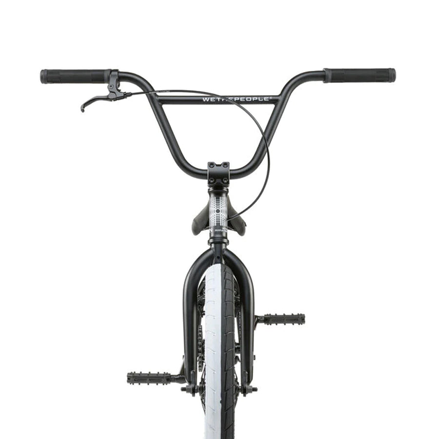 Front view of the Wethepeople Nova 20 Inch Bike, highlighting black Salt Rookie Cranks, sleek handlebars, a brake lever, pedals, and a striking white front tire.