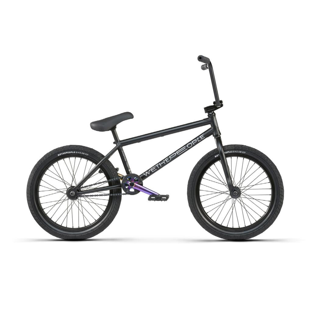 The Wethepeople Reason Shift 20 Inch Bike is a premium black BMX with a chromoly frame, flat seat, thick tires, and distinctive purple pedal cranks.