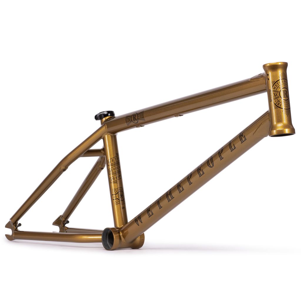 The Wethepeople Revolver Frame (2022) in gold metallic, with its intricate engraved designs and durable black seat clamp, provides a versatile frame experience backed by a lifetime guarantee.