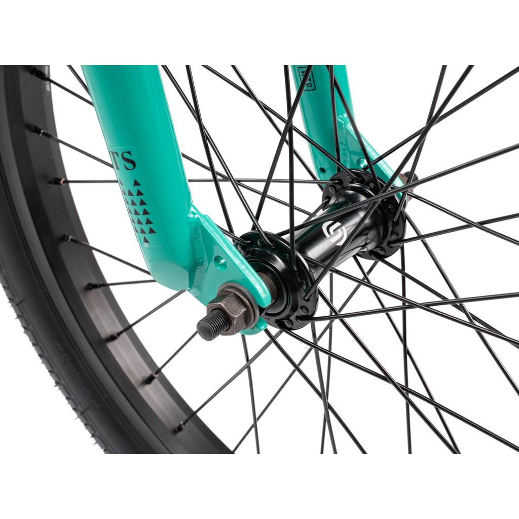 Close-up of the Wethepeople Thrillseeker 20 Inch Bike's front wheel with black spokes, hub, and teal fork with visible nuts and bolts, perfectly paired with Salt Thrillseeker handlebars.