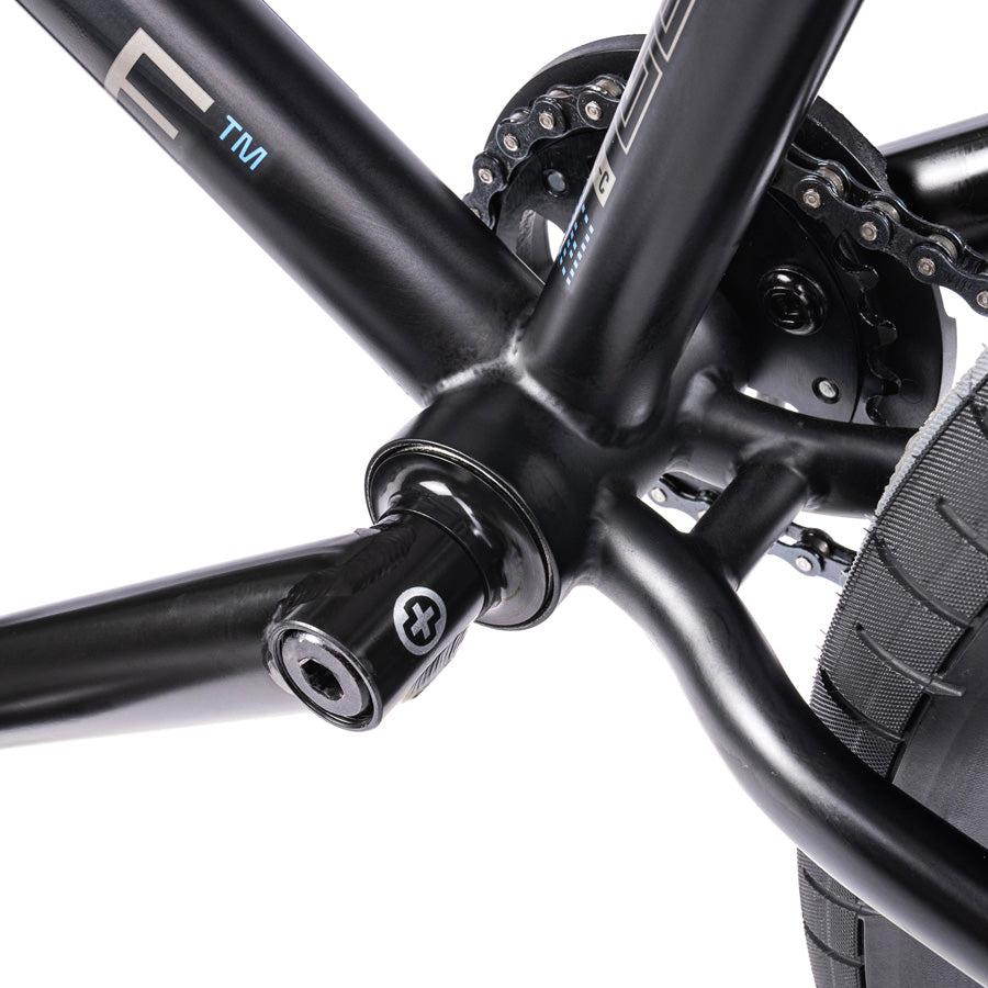 Close-up of the Wethepeople Trust 20 Inch Freecoaster/Hybrid Bike's black frame, highlighting the bottom bracket, pedal crank, as well as a portion of the chain and rear wheel.