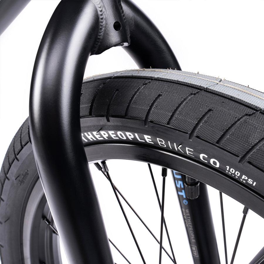 Close-up of a tire from the Wethepeople Trust 20 Inch Freecoaster/Hybrid Bike, featuring a black sidewall marked with "WETHEPEOPLE BIKE CO" and indicating 100 PSI, showcasing precision comparable to battleship geometry.