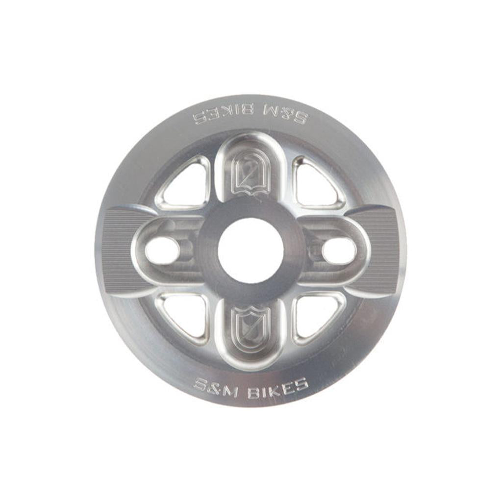 The S&M X-Man Guard Sprocket is a CNC machined silver bike sprocket made from durable aluminum, featuring the engraved text "S&M Bikes," designed in a circular pattern with multiple attachment holes.