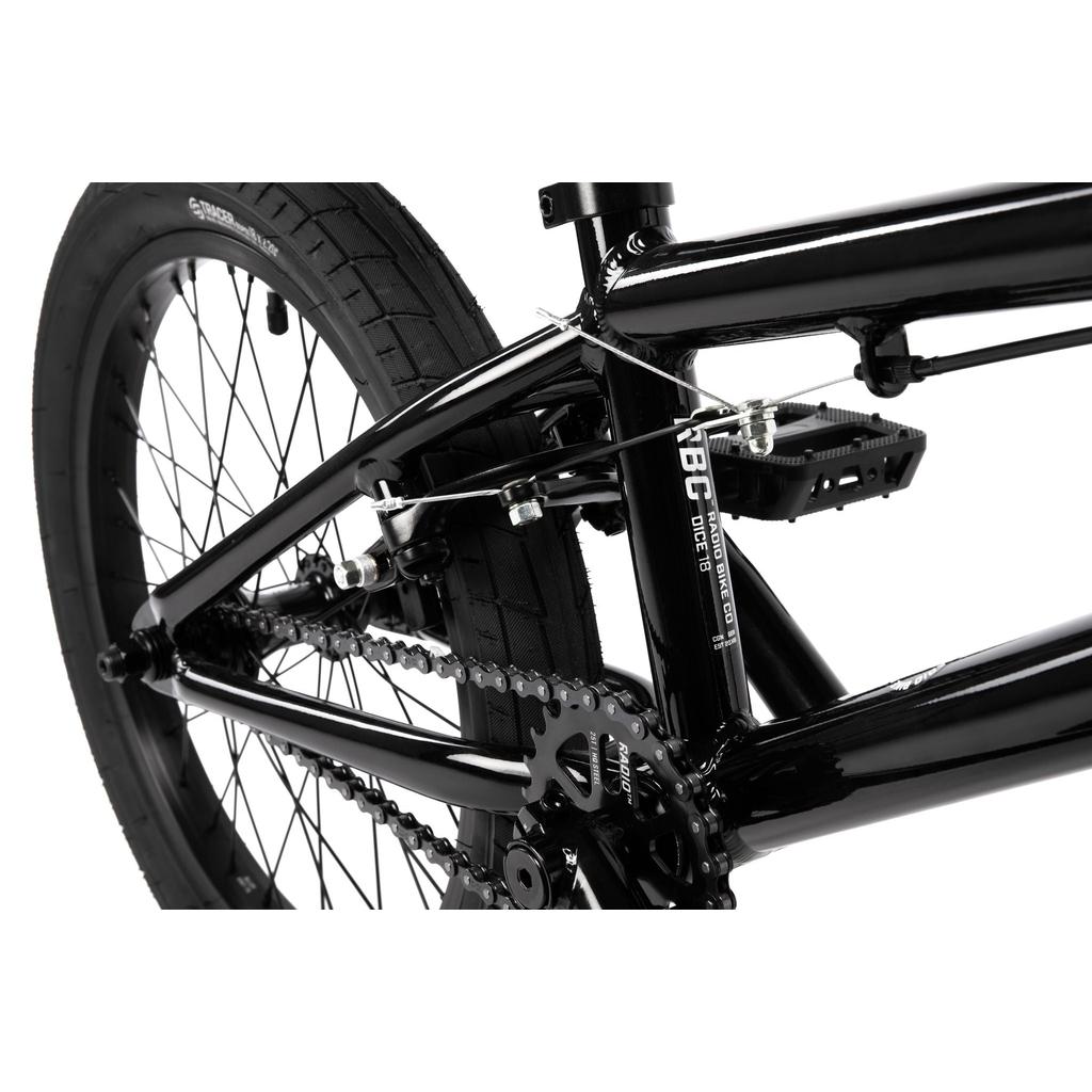 Close-up of the rear wheel, Radio Rookie Three Piece Cranks, and chain on a black Radio Dice 18 Inch Bike with Salt Tracer Tyres against a white background.